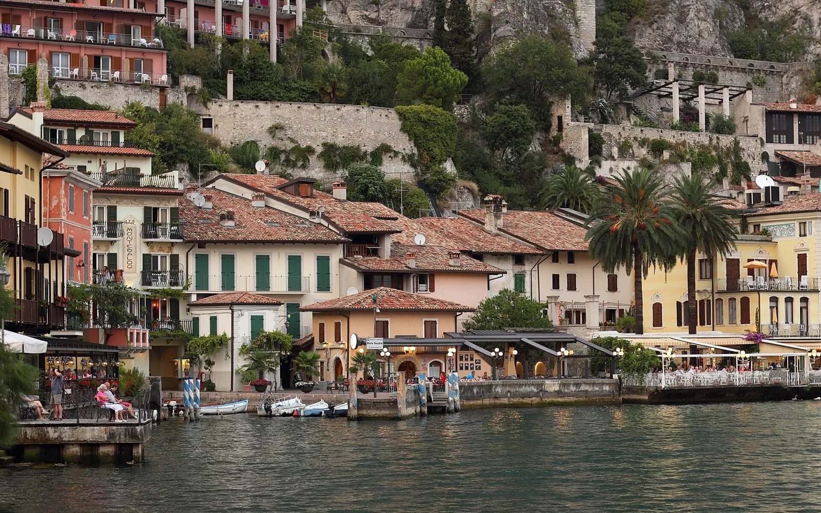 Le case colorate e il Porto Vecchio di Limone sul Garda al tramonto, ai piedi della parete rocciosa